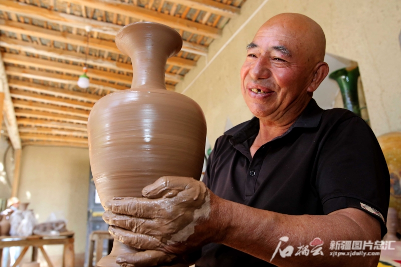 6月19日，英吉沙縣芒辛鎮(zhèn)恰克日庫(kù)依村土陶非遺傳承人阿卜杜熱合曼·麥麥提敏在欣賞剛制作的土陶作品。石榴云/新疆日?qǐng)?bào)記者 蔡增樂 攝