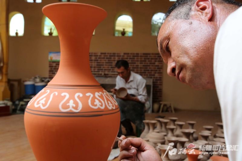 6月19日，恰克日庫(kù)依村土陶制作藝人伊馬木·艾力在土陶罐上畫畫。石榴云/新疆日?qǐng)?bào)記者 蔡增樂 攝